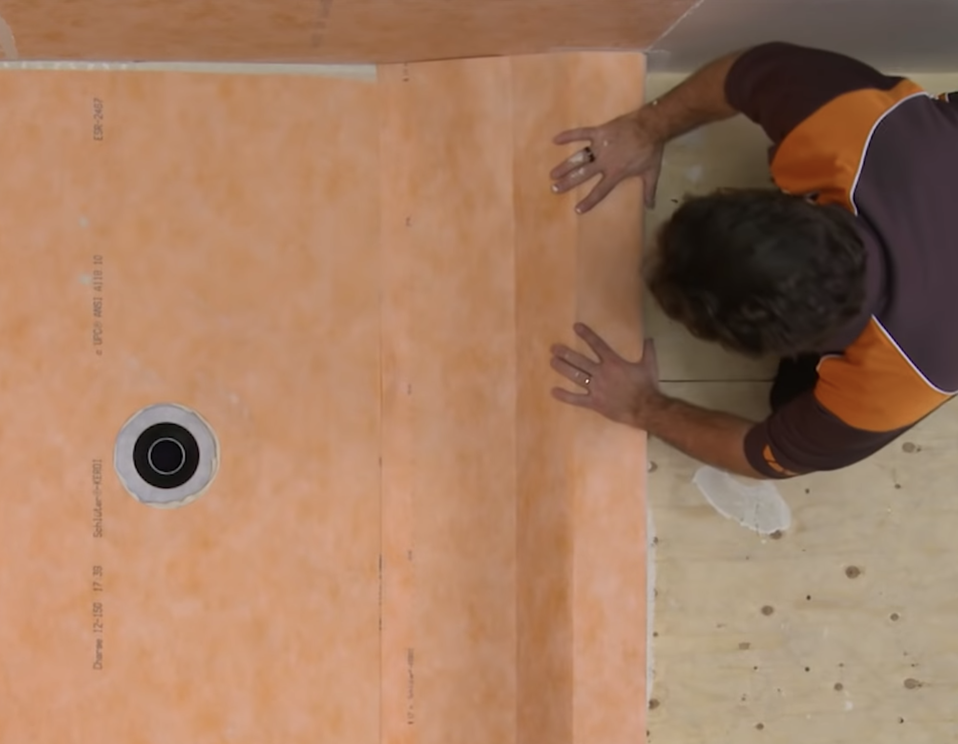 A man is shown assembling a shower frame with easy to align and cut Schluter boards.